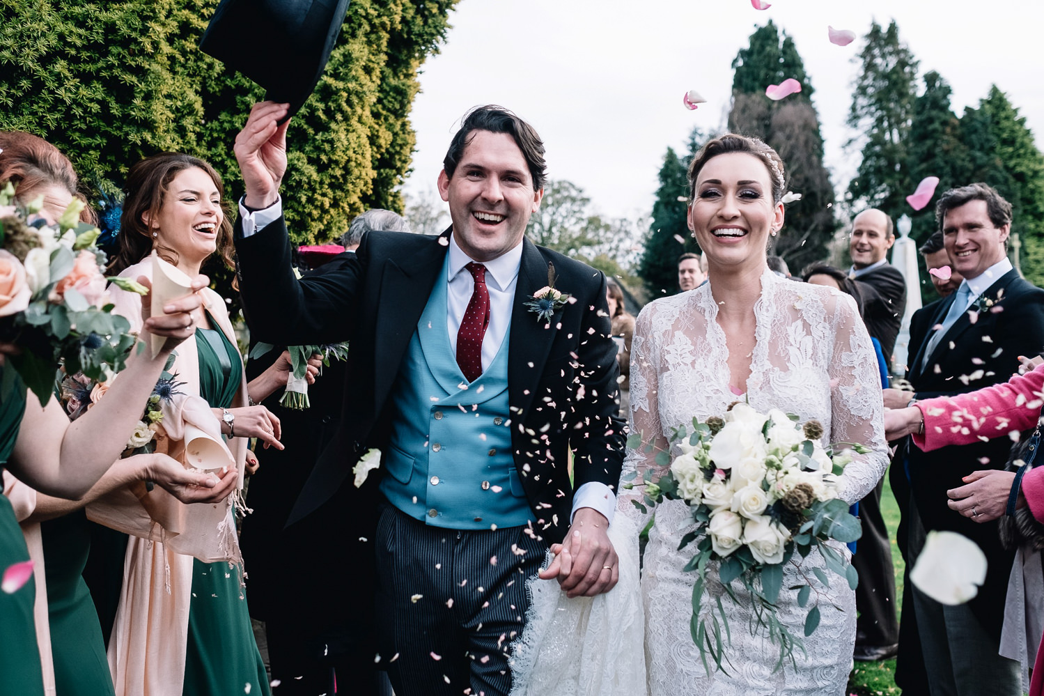 Groom takes off top hat during confetti walk.