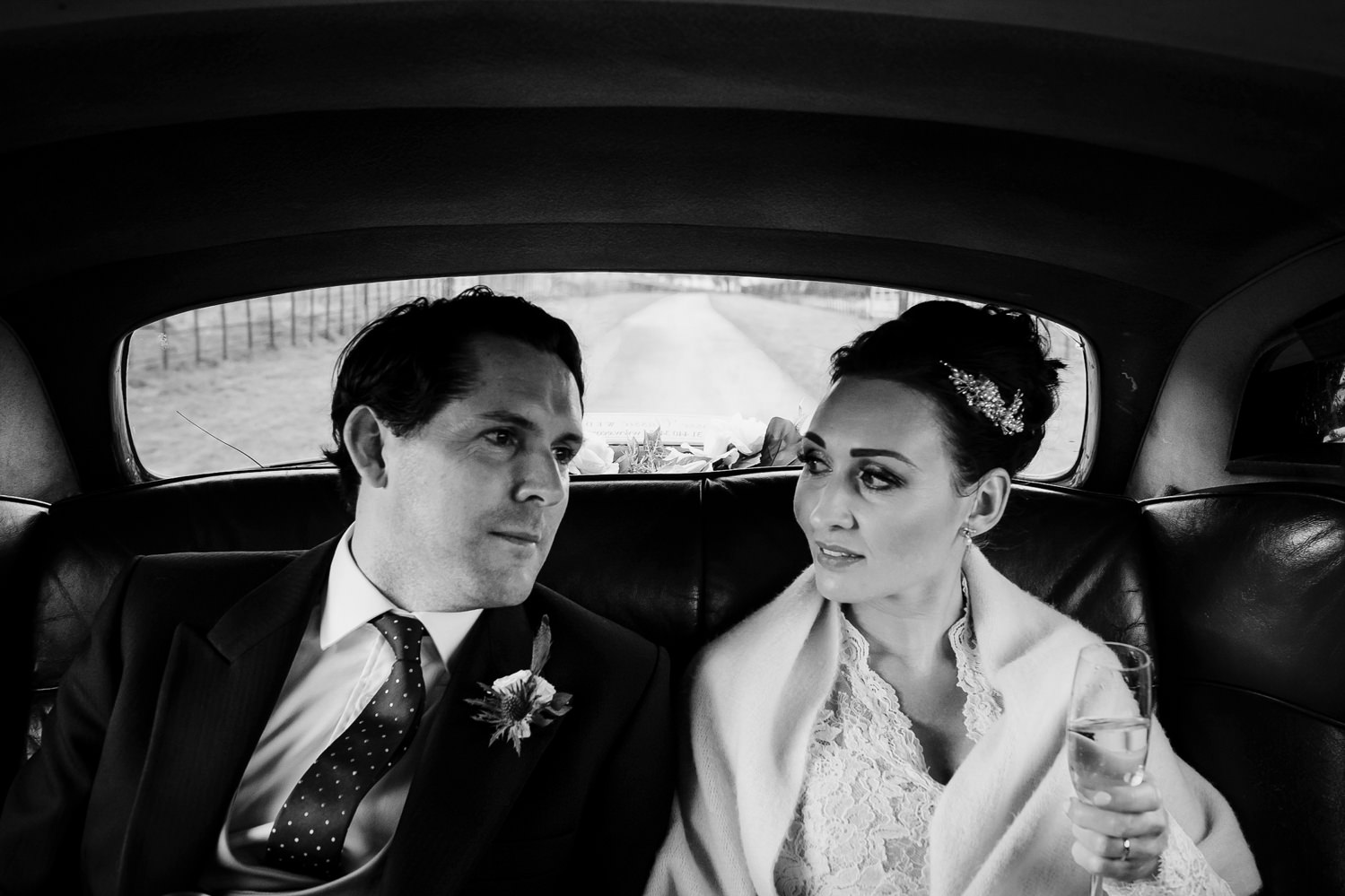  Couple sit in back seat of Bentley on a winter wedding day 