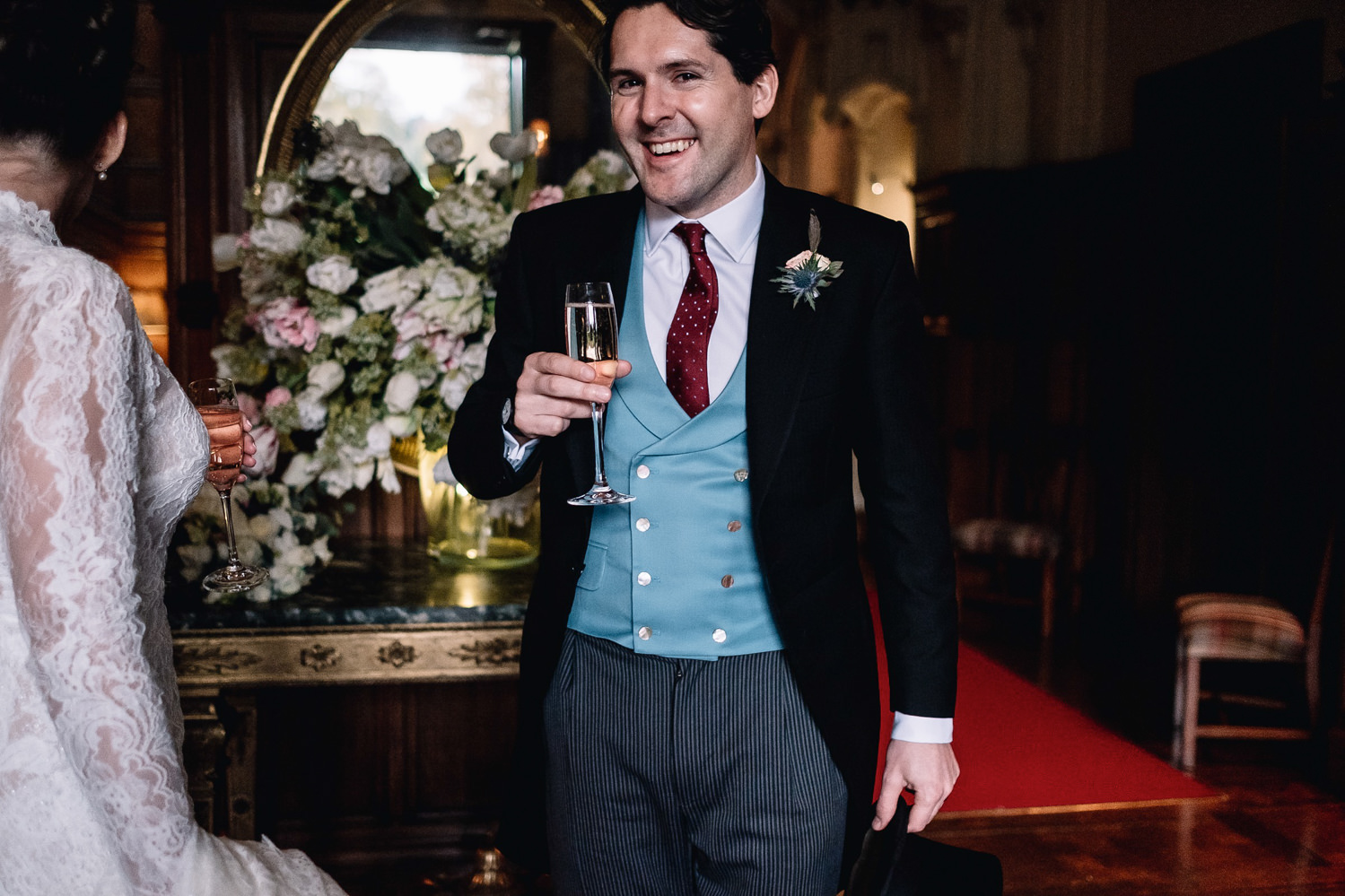 smilng groom holds his Champagne glass