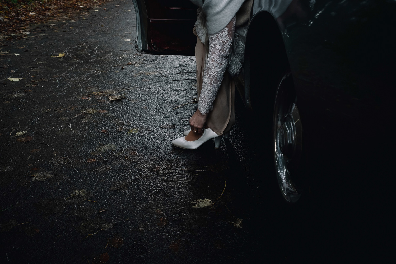  Bride leans out of Bentley to change her footwear on a winter's day 