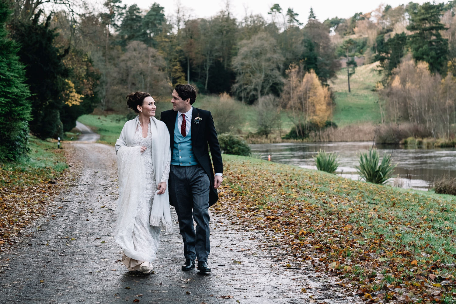  couple walking next to loch by the Dundas Castle Boathouse on their winter wedding day 
