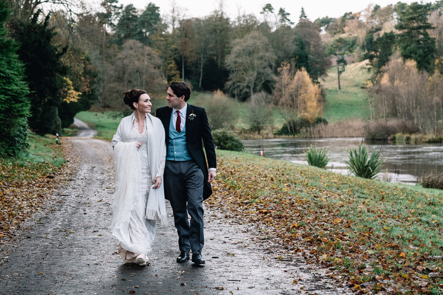 couple walking next to loch by the Dundas Castle Boathouse on their winter wedding day