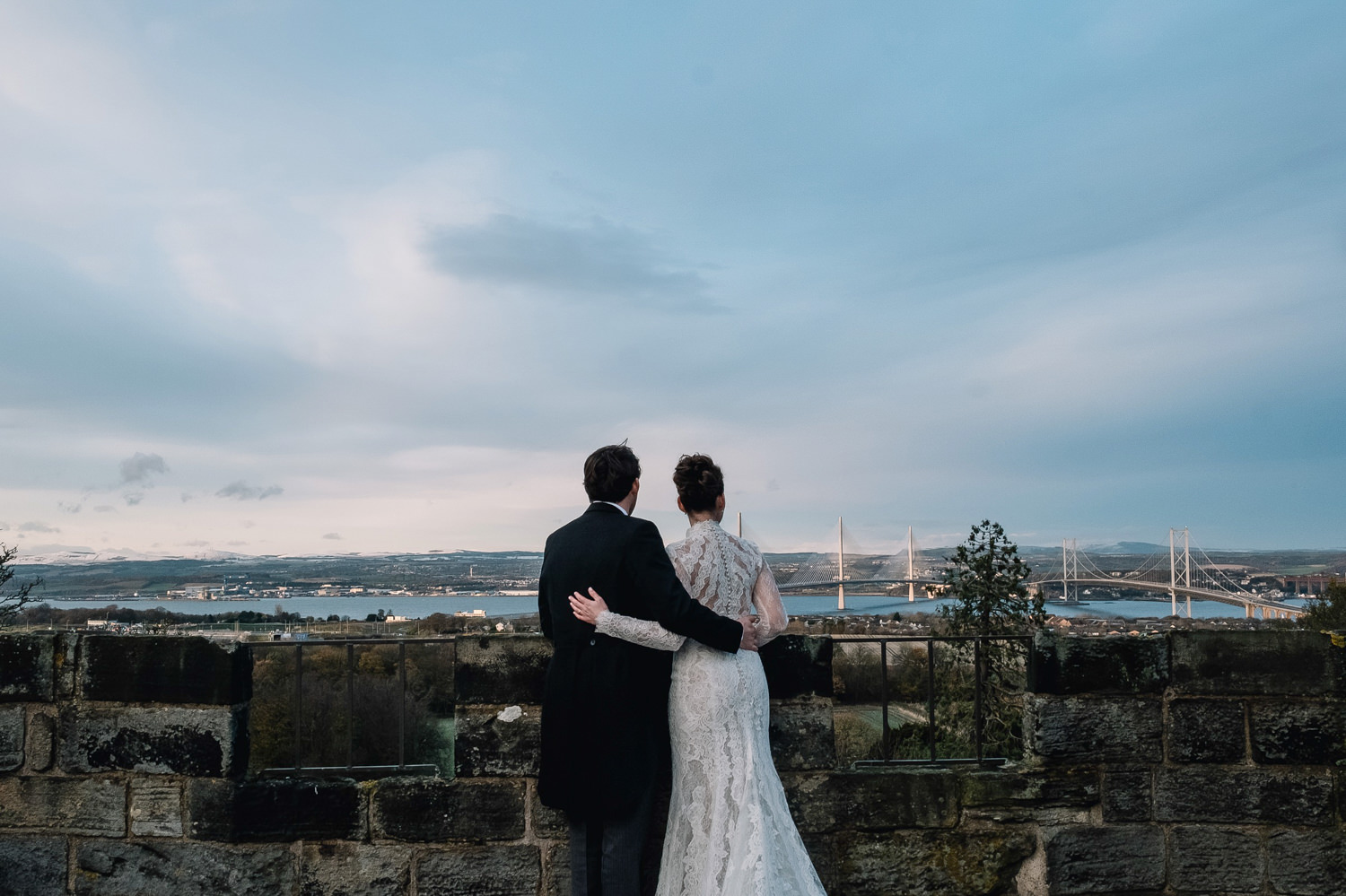 couple stand looking at view of edinburgh on a winter wedding day 