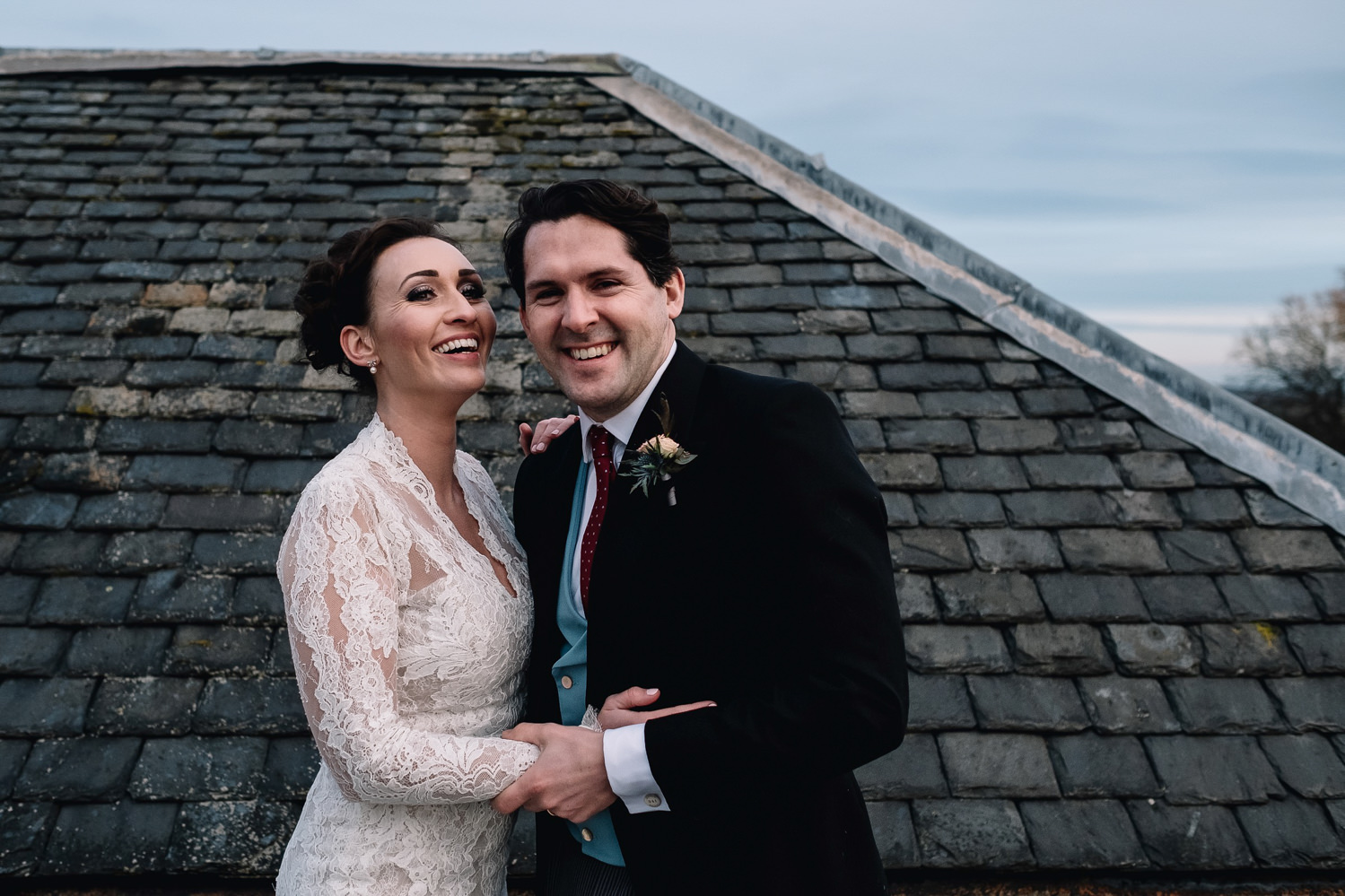  laughing bride and groom on rooftop of Dundas Castle's keep 