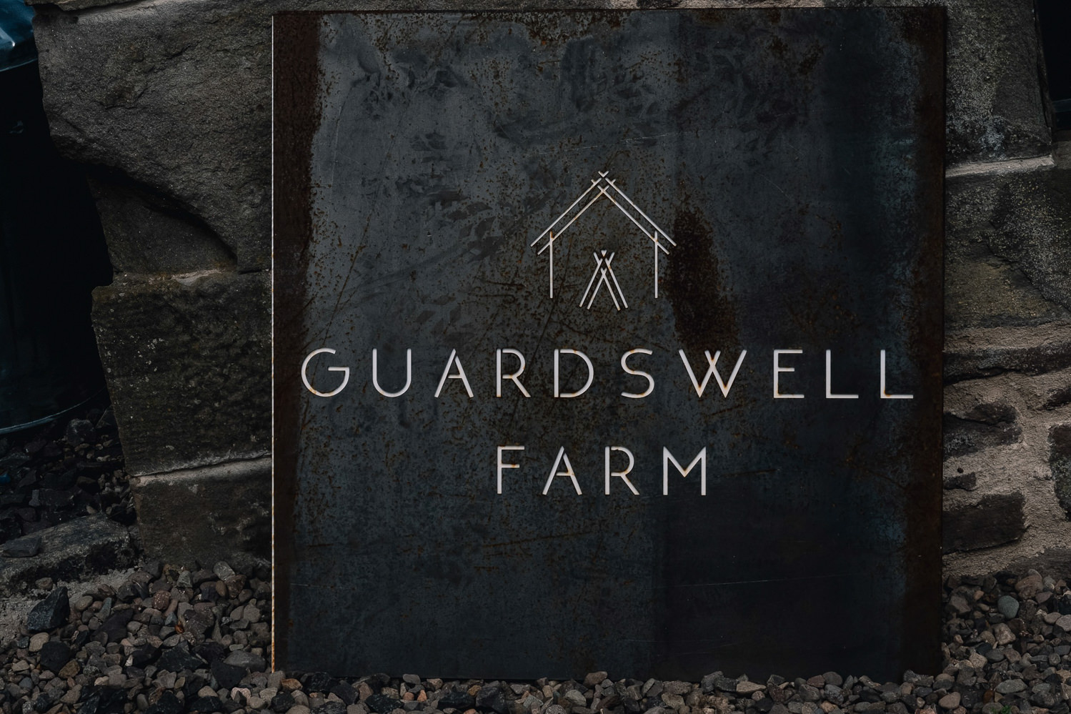Slate with name and branding logo of Guardswell sits on the ground.