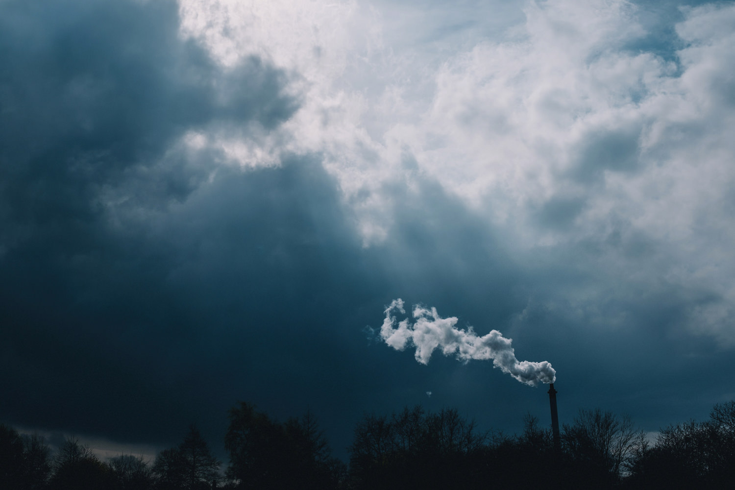 Stormy blue skies contrast against industrial smoke.