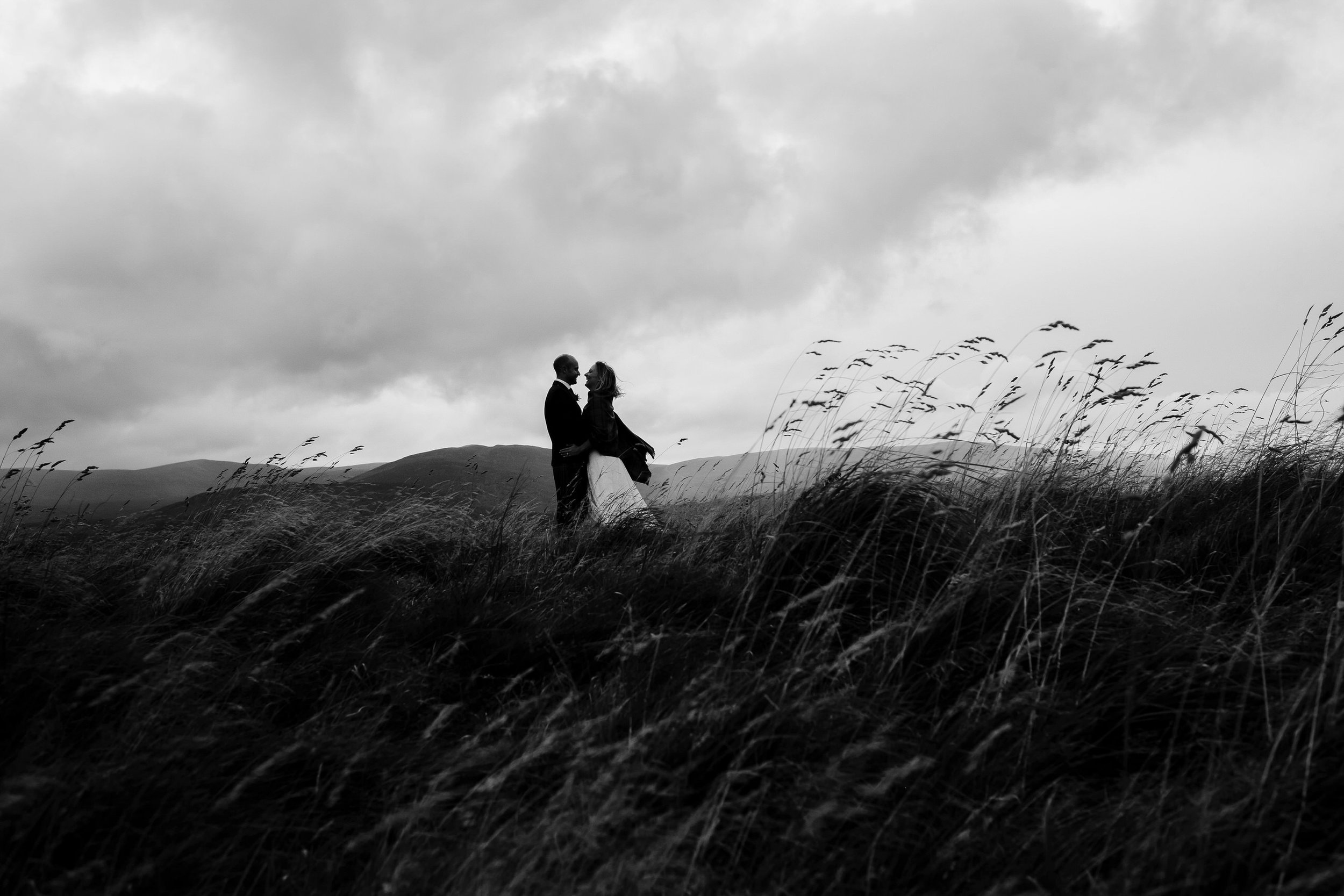  Bride and groom stand in open fields of Kingussie during their small intimate Scottish wedding 