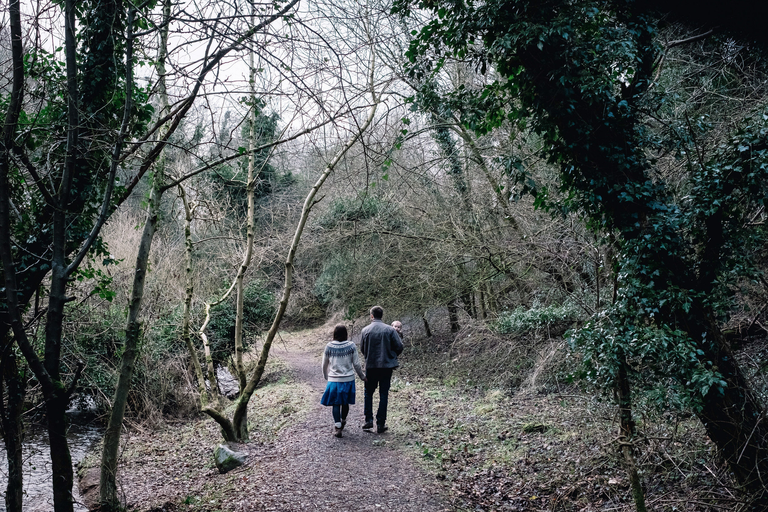 Family of three are walking in a forrest.