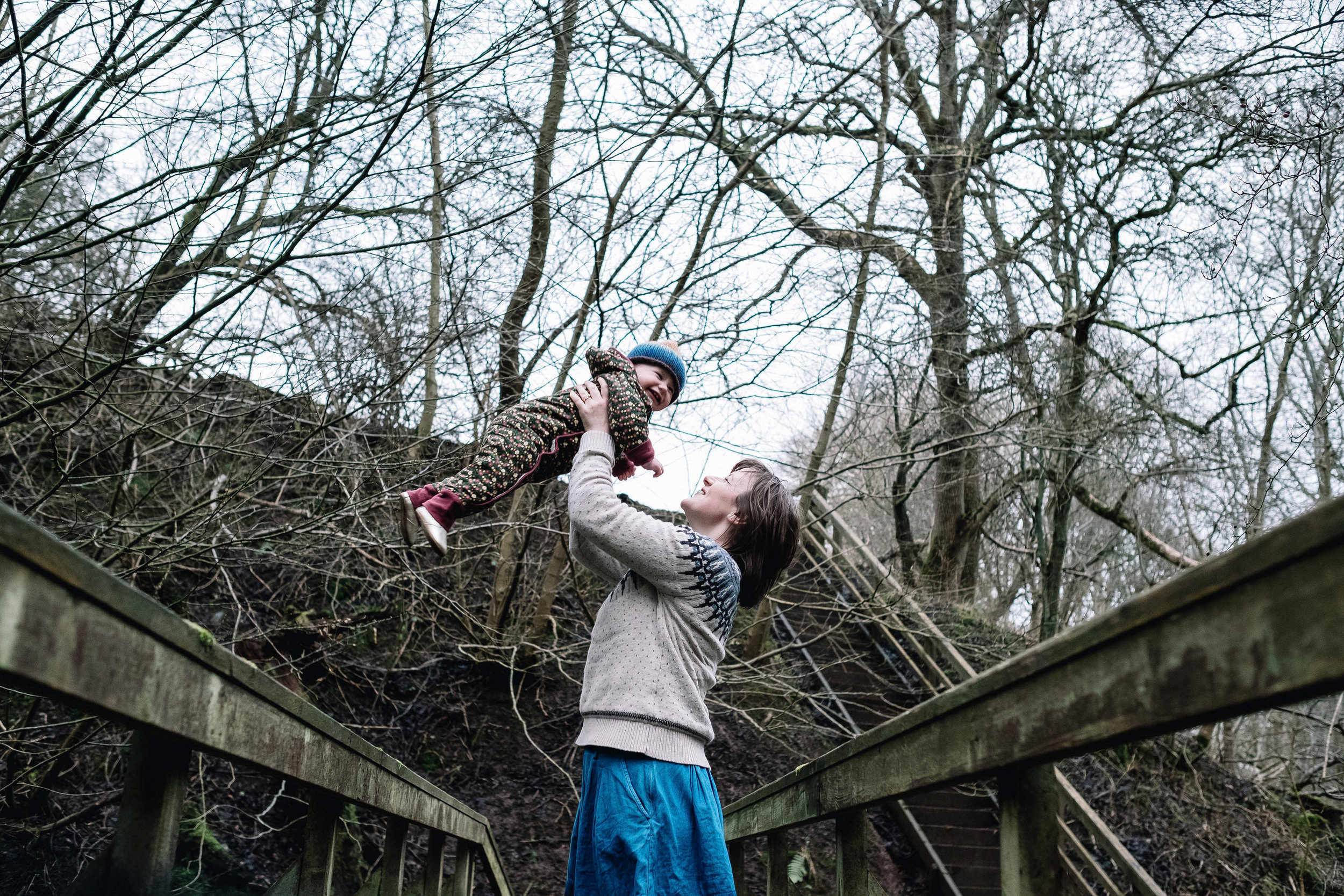 Mother stands on bride and holds her daughter up high.