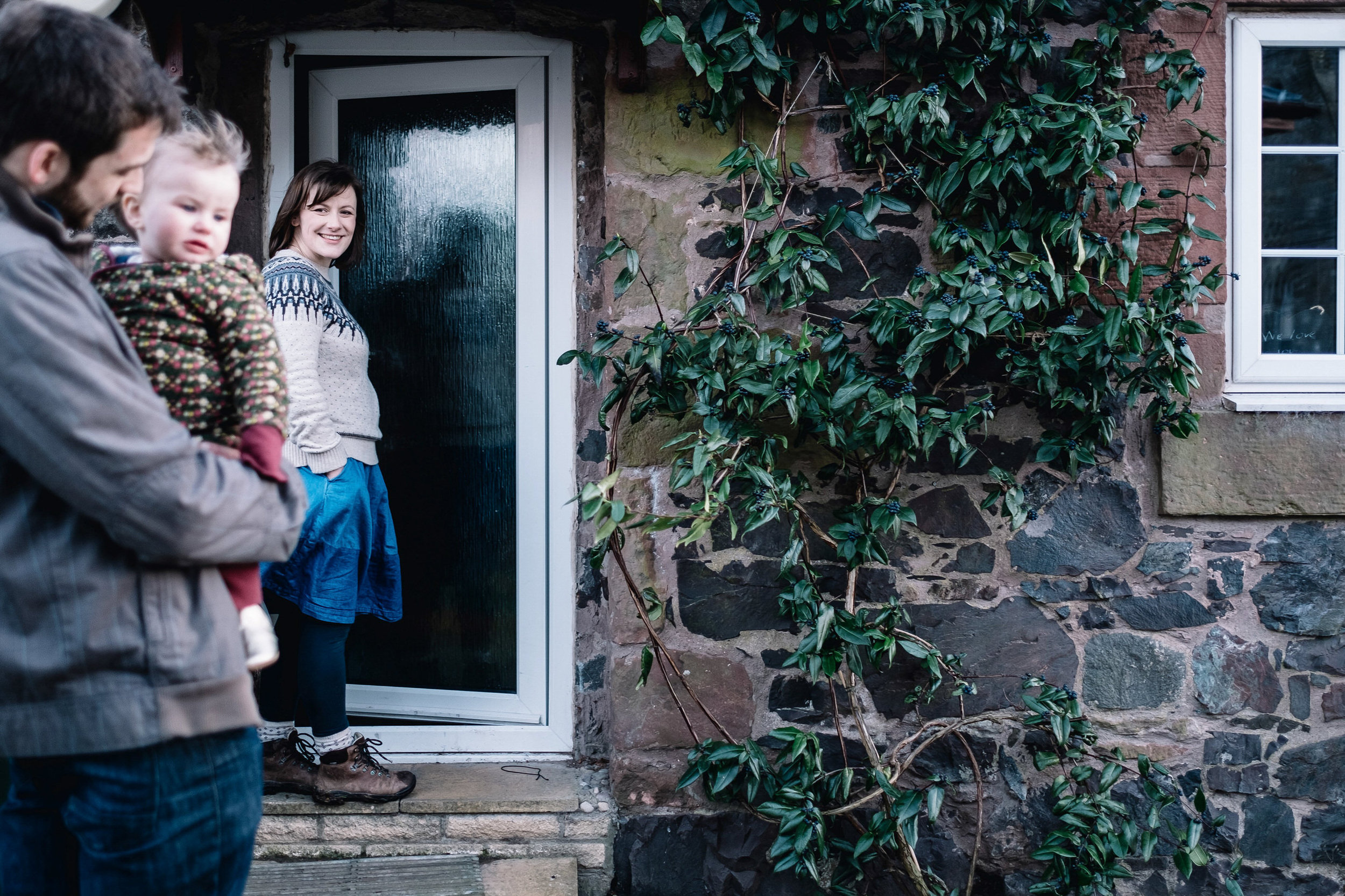  Mother opening door to their house. Father holding daugher. 