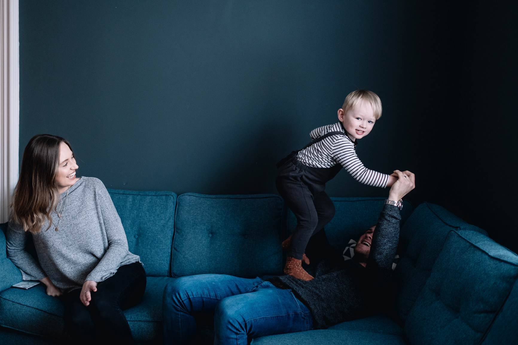 A young boy is jumping on his father's stomach.