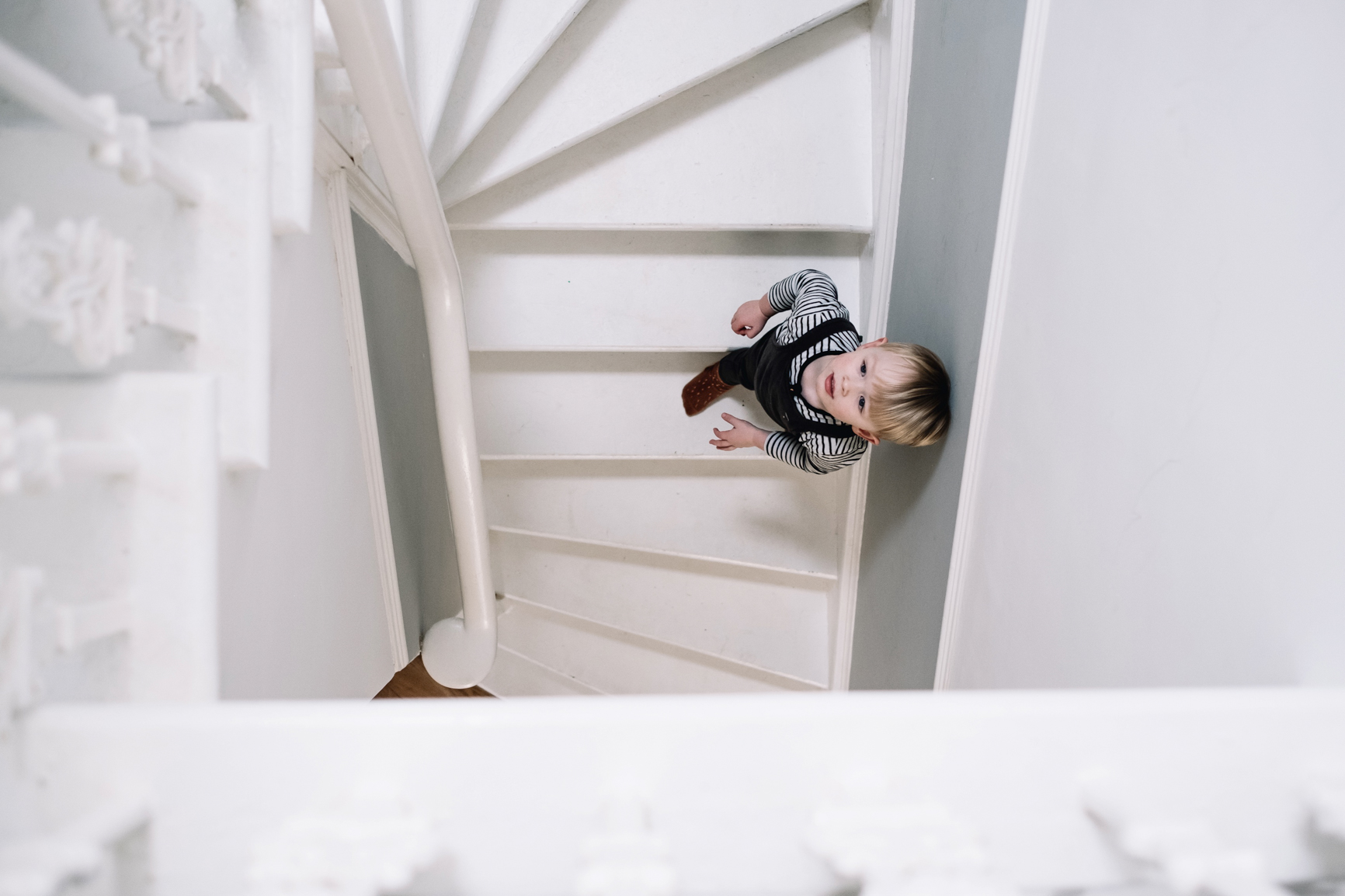  A young boy is walking down a spiral stair case. 
