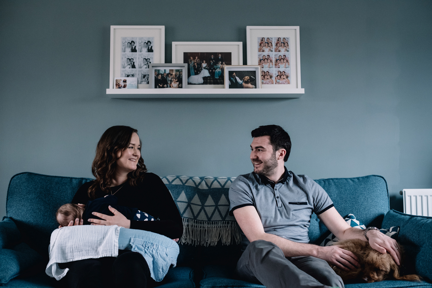 Mother and father sitting on sofa smiling at each other.
