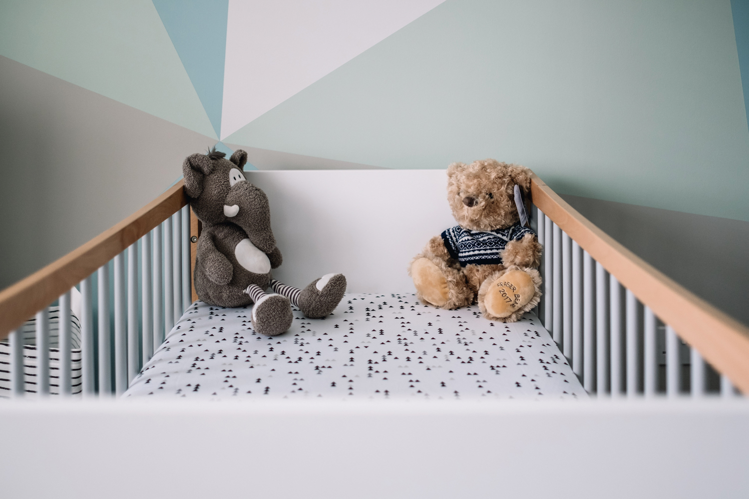  Two teddies are at the top of a baby's cot. 