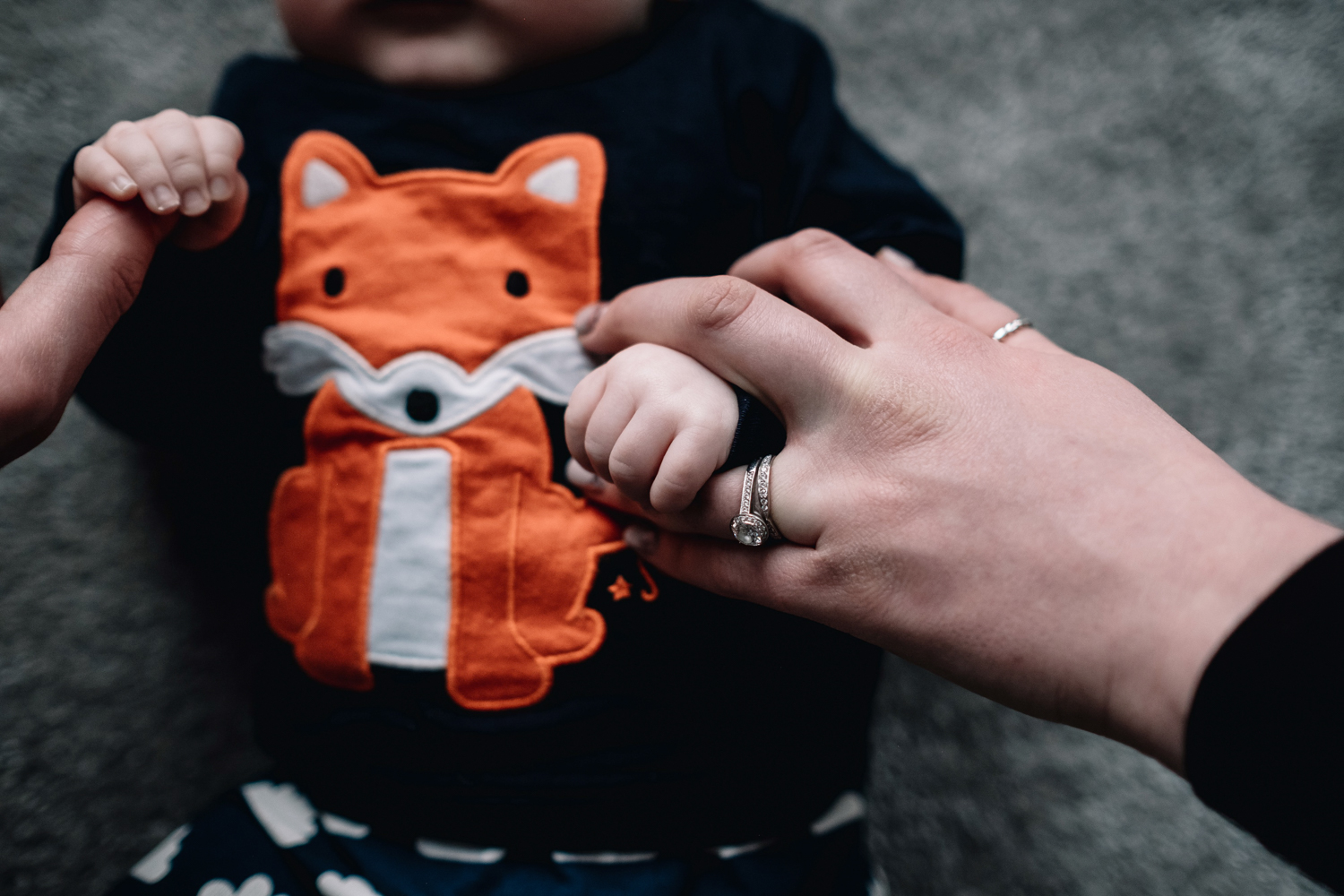 Mother holding baby boy's hand.