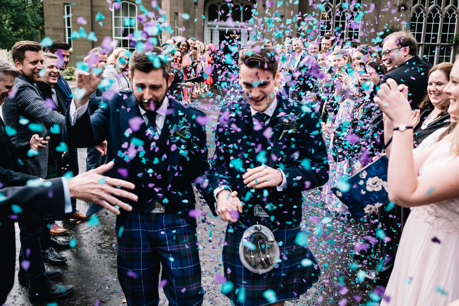  A couple laugh and run as they are showered with purple and blue confetti. 