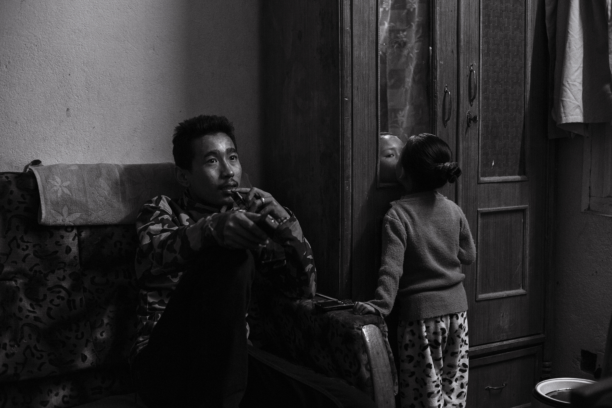 Brother Anil (20) watches a tv set given to him by a friend as Anjika plays nearby.