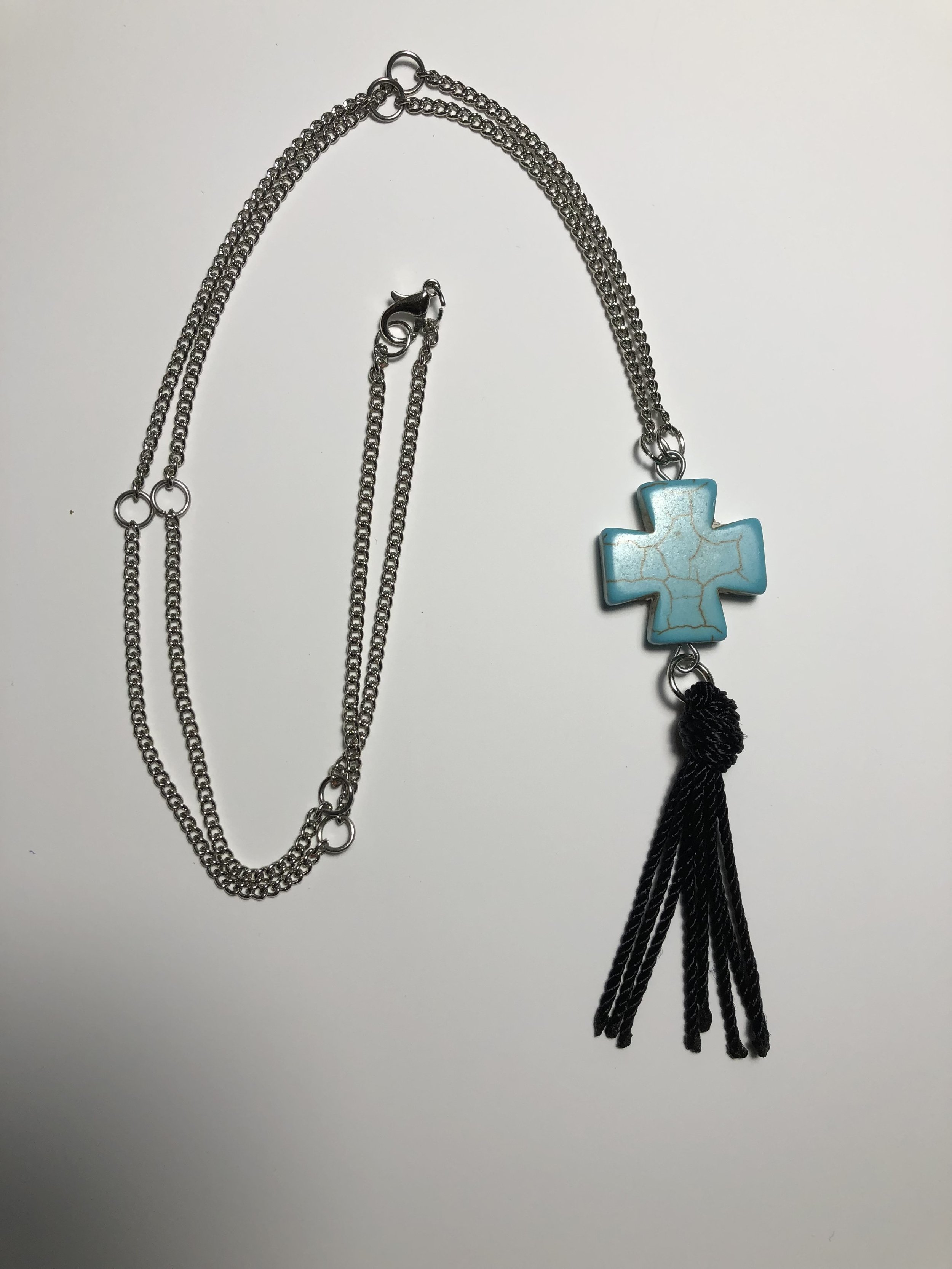 Pendant necklace adorned with cross tassel.