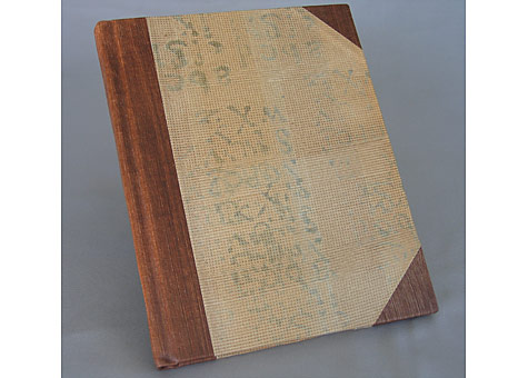 Binder/Artist: Marie Kelzer: A Blank Book-The Fading Word. Paper Arts, San Francisco, 2006. Hand bound blank book sewn on linen tapes. Half bound with faux leather spine and corners; hand painted with acrylic on canvas. The boards are covered with hand decorated paste papers by the binder, using a letter stamp. The blankness of the book symbolizes the fading use of words with shorthand, email and text messaging, the word continues to diminish.