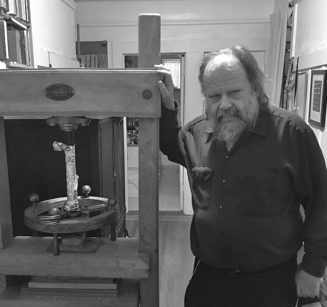 Tom Conroy with his bookbinding press. Credit: Jeff Peachey