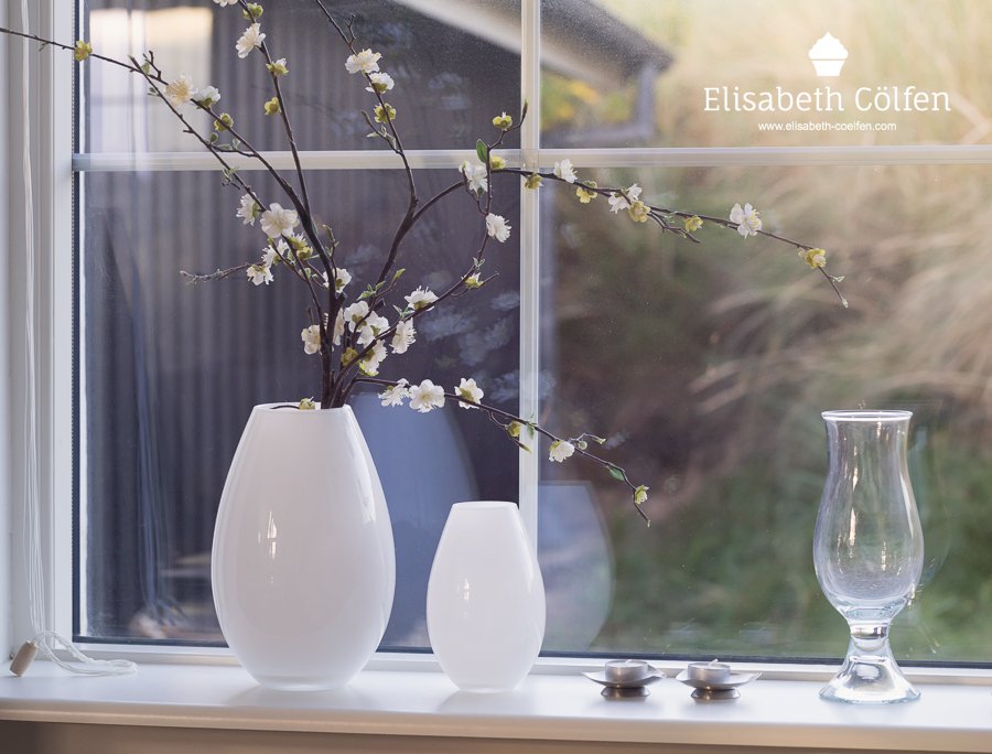 Bouquet of artificial cherry blossoms and vases in a window in a holiday home at the beach