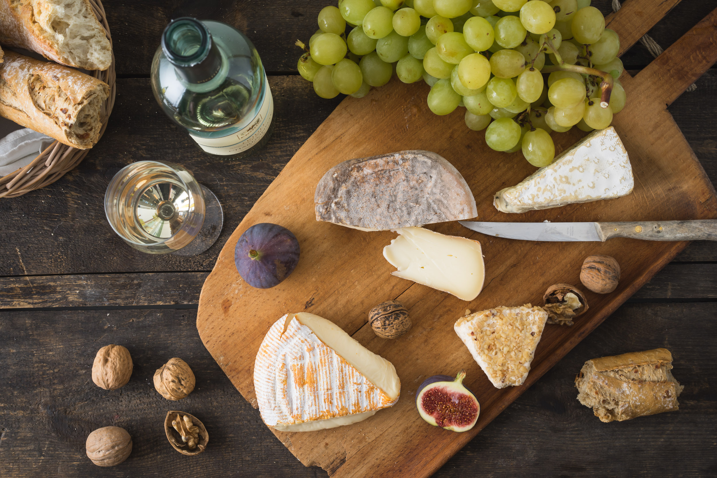 Käseplatte mit Camenbert, Walnusskäse, Gorgonzola, Taleggio, dazu Weißwein, Weintrauben, Feigen, Nüsse und Baguette