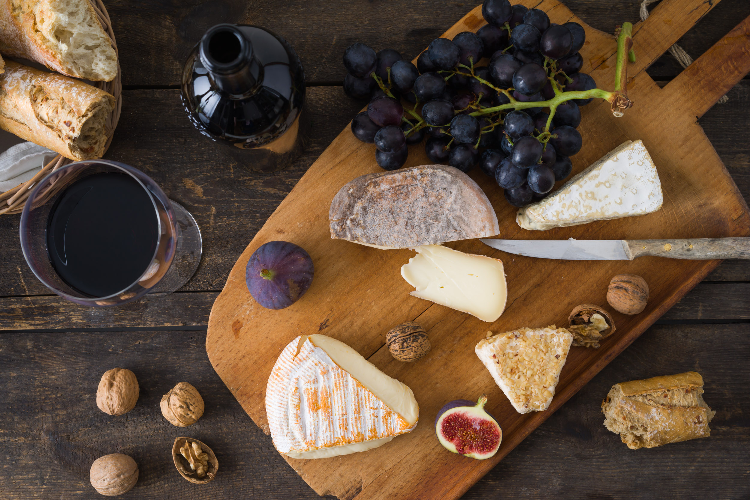 Käseplatte mit Camenbert, Walnusskäse, Gorgonzola, Taleggio, dazu Rotwein, Weintrauben, Feigen, Nüsse und Baguette