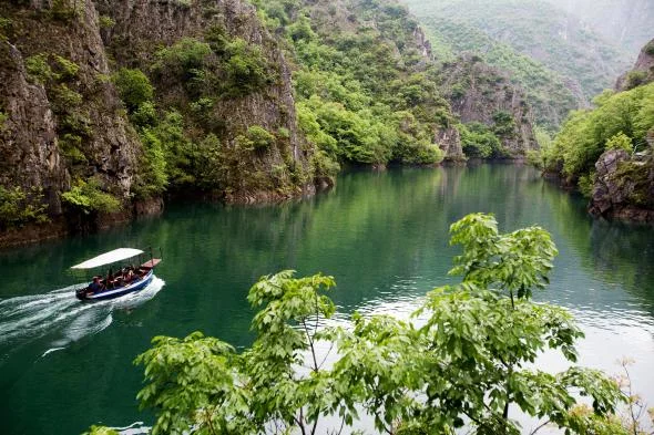 A boat glides past the emerald landscape in Matka Canyon. PHOTOGRAPH BY IMAGES & STORIES, ALAMY STOCK PHOTO