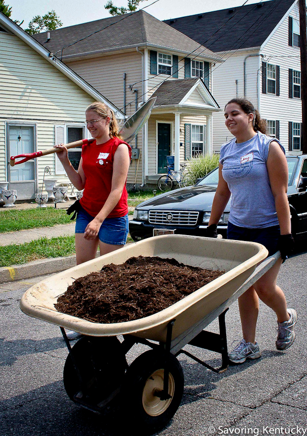 Student volunteers from the University of Kentucky move finished compost to nurture a garden