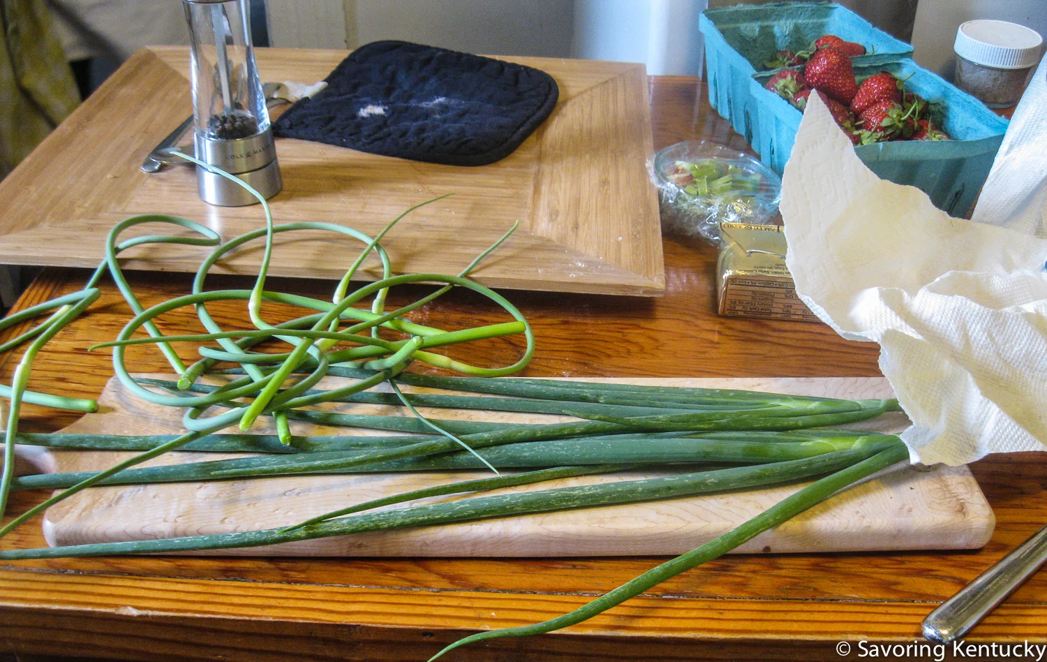 Campsie garden garlic scapes and green onions ready to add their mild, spring-y, pungent flavors. Elmwood Stock Farm organic strawberries in the background.