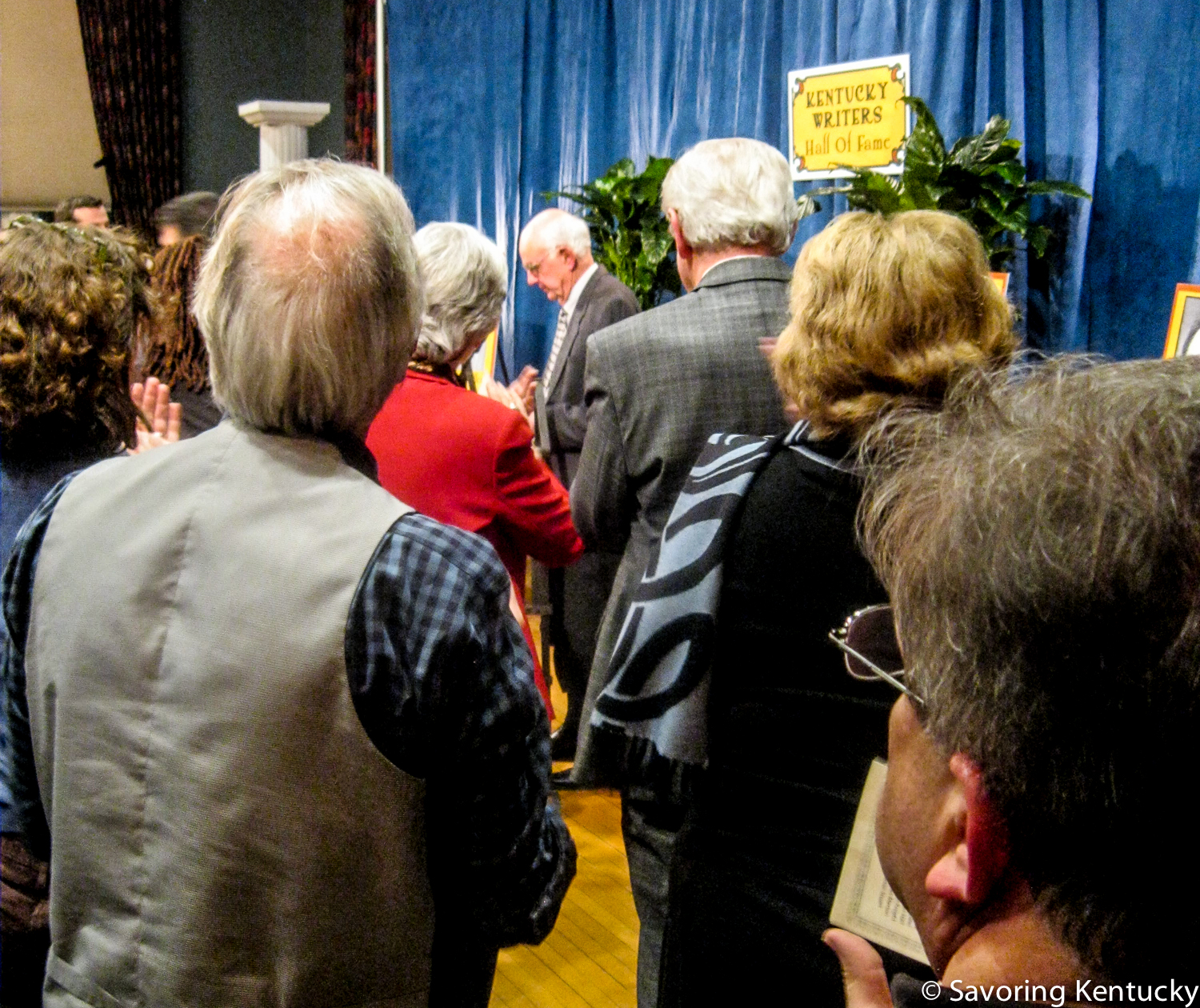 Wendell Berry at center. From back left, photographer and artist Guy Mendes in vest, Kentucky Lieutenant Governor Crit Luallen in red. From back right, Kentucky Monthly editor and publisher Steve Vest, Kentucky Arts Council director Lori Meadows, Lynn Luallen.