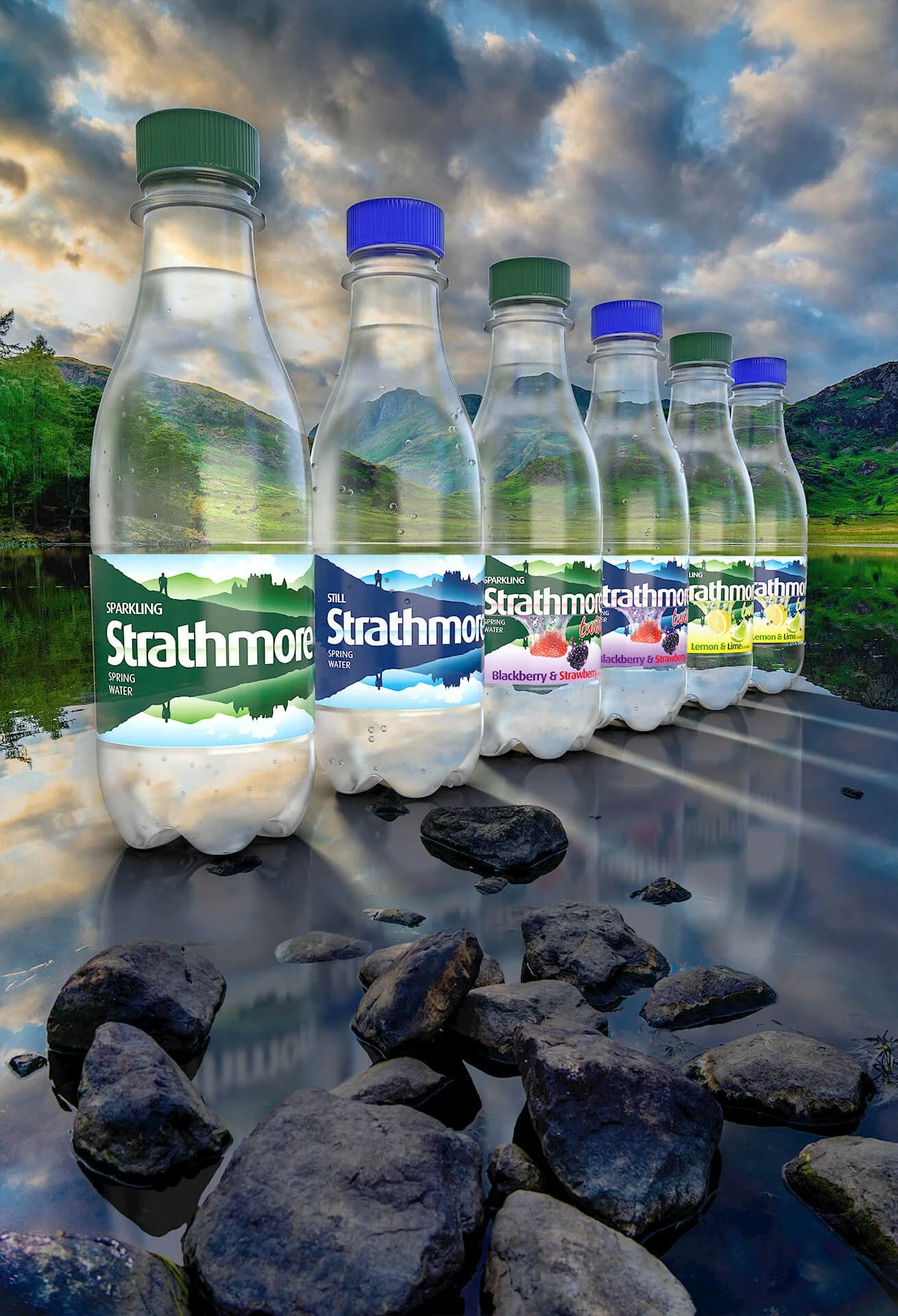 Gallery hero shot of six Strathmore spring water bottles on reflective wet stones, set against a dramatic landscape with lush hills and a vibrant cloudy sky.