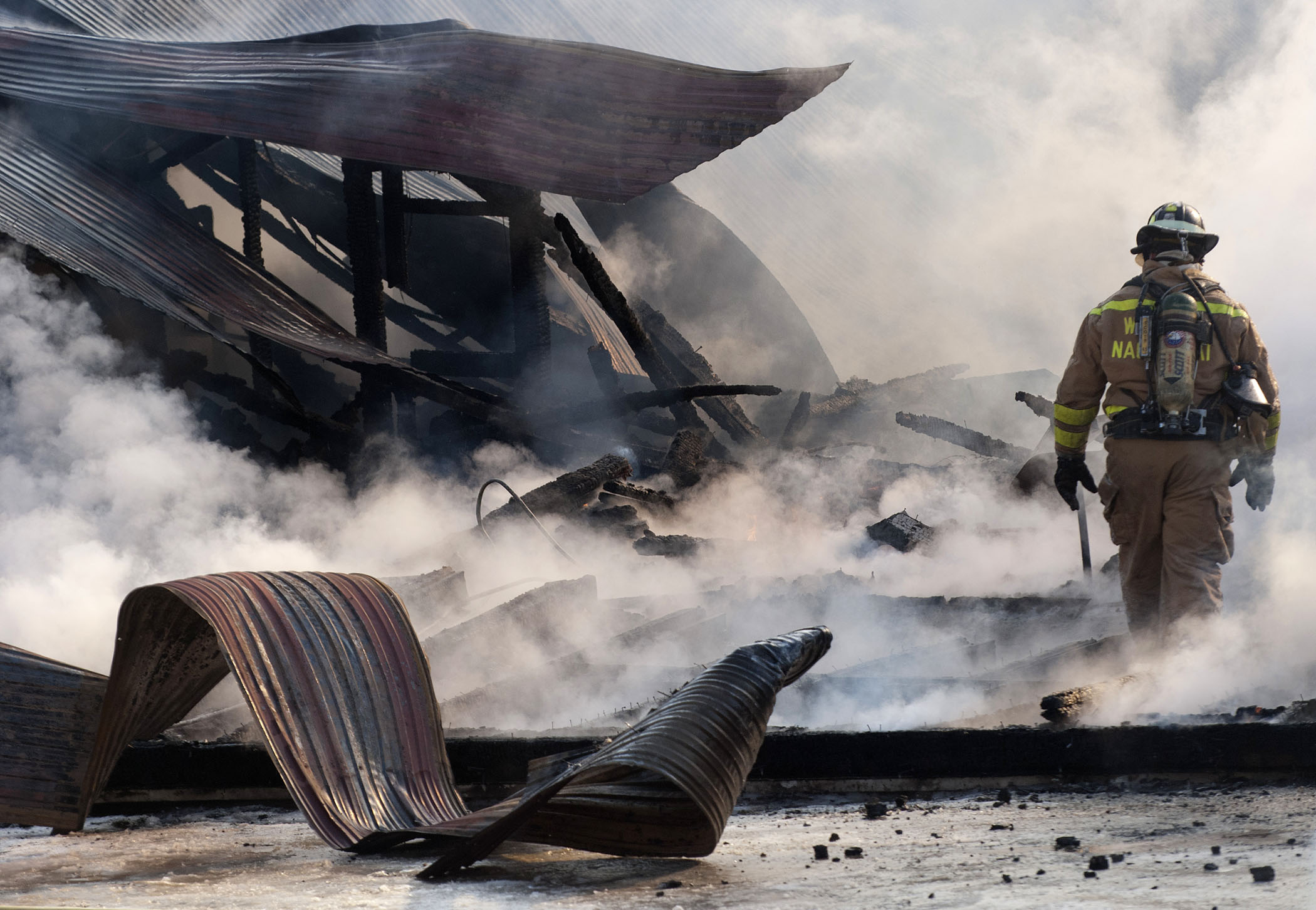 A firefighter walks through debris as firefighters work to keep flames under control at a barn fire on County Rd. in Walpole, N.H. on Friday, January 3rd.