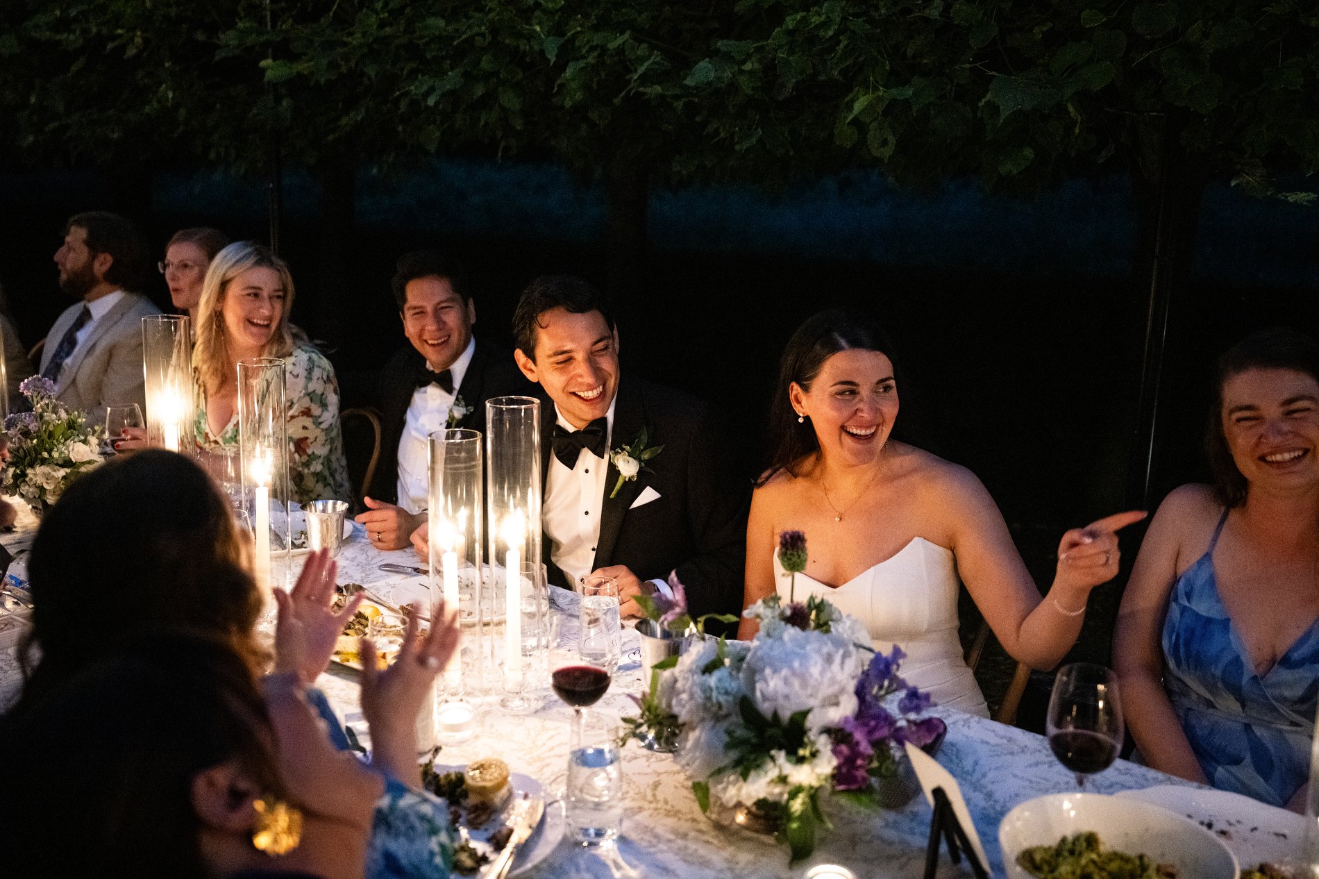A couple laughs with friends during an intimate dinner at long tables during a microwedding at The Mount in the Berkshires.