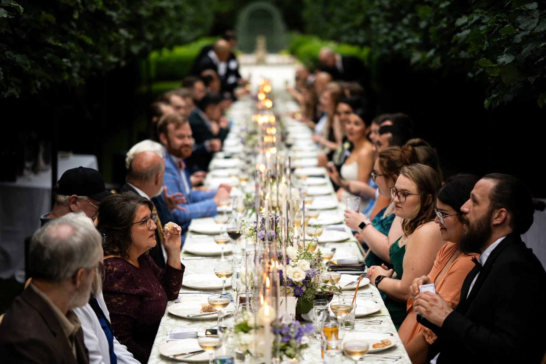 Guests sit at a long table during a wedding dinner in the Lime Walk at The Mount.