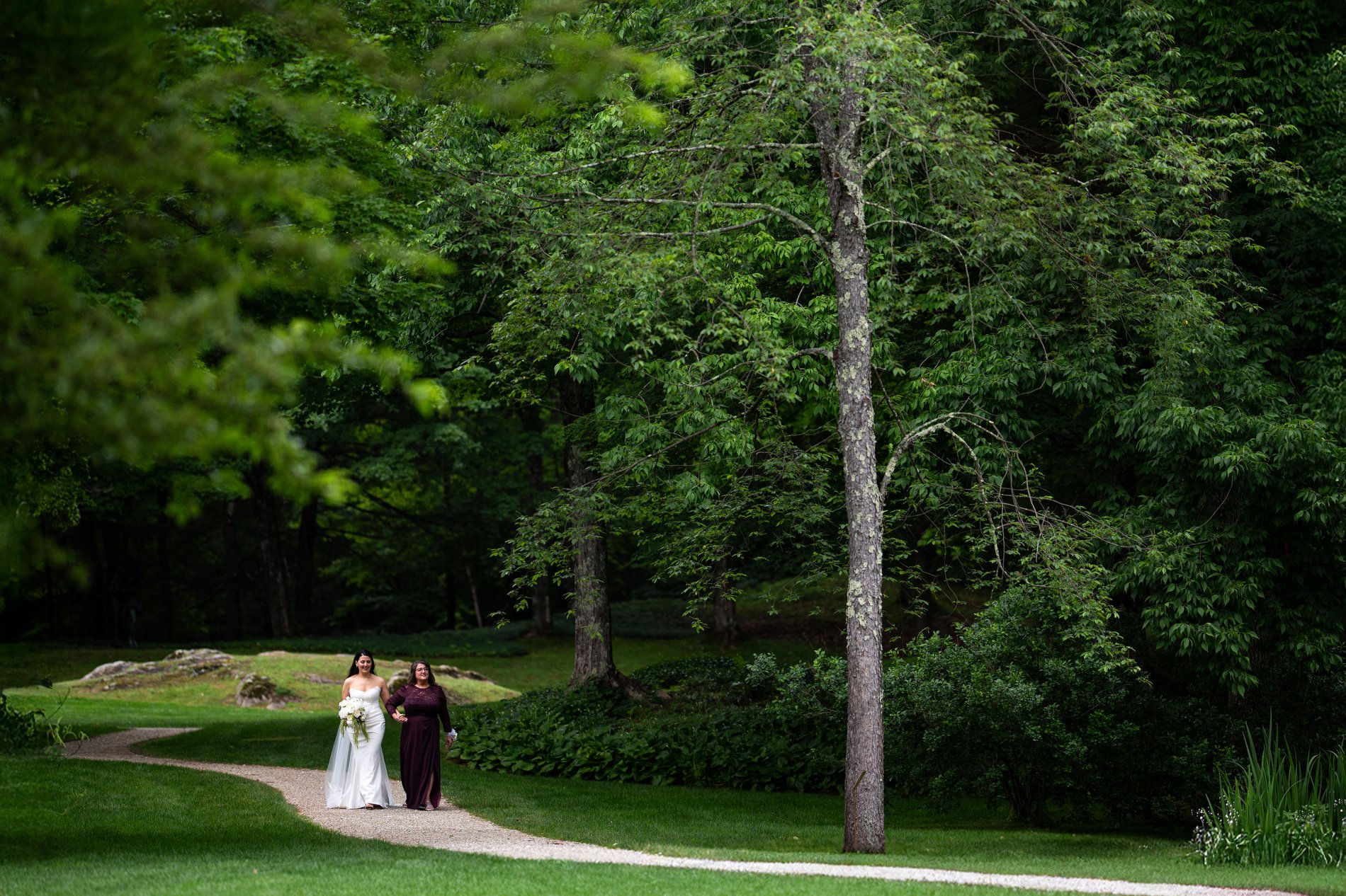 A bride walks down the aisle with her mom during her romantic microwedding at The Mount in Lenox, Massachusetts.