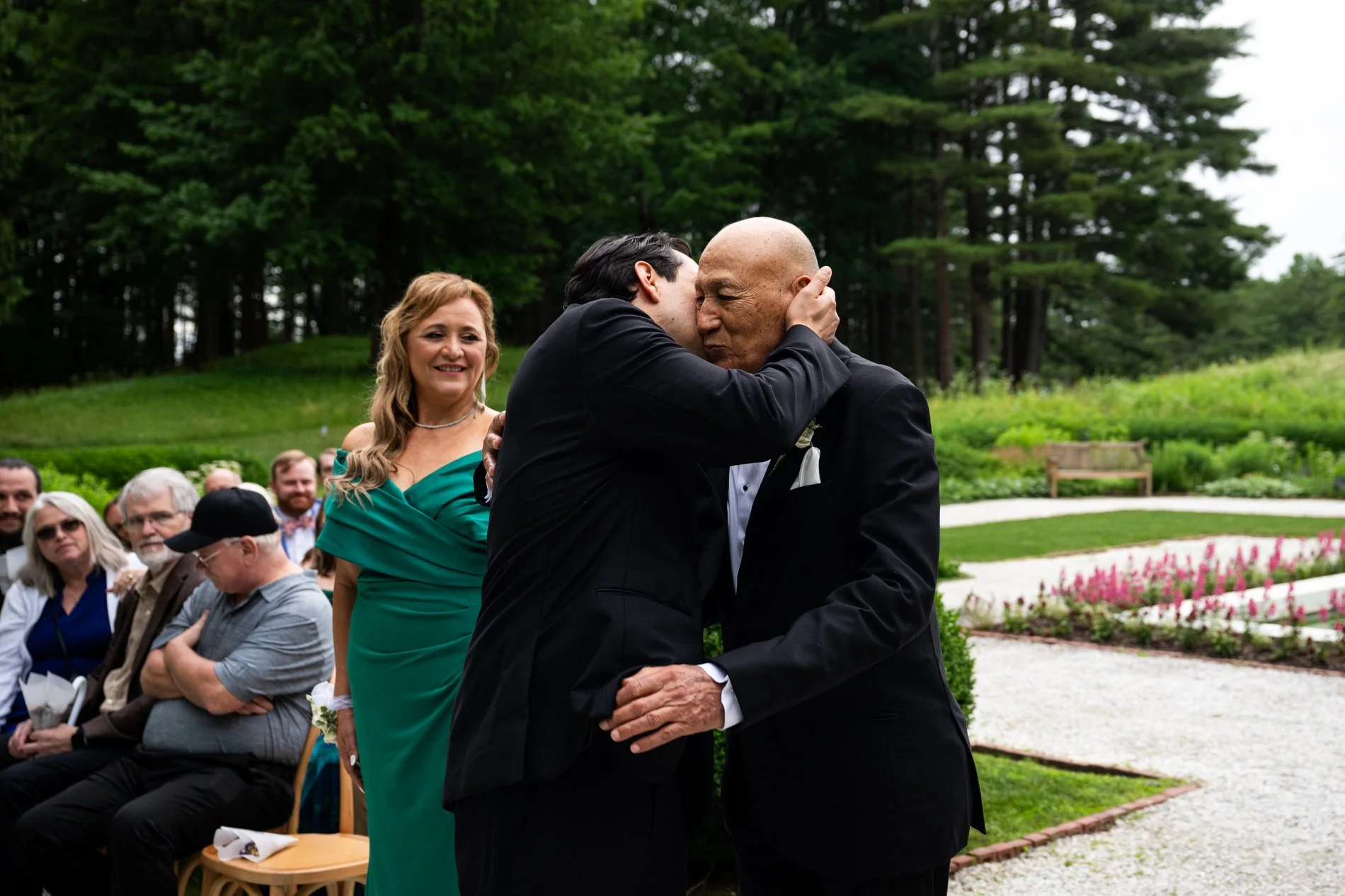 A groom embraces his father during his Berkshires microwedding ceremony in the French garden at The Mount.