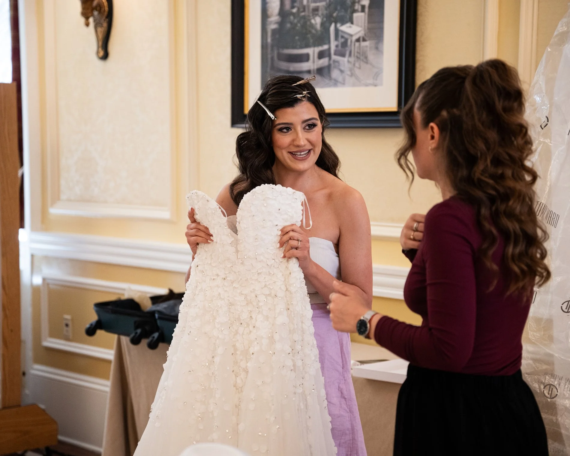 A bride holds her wedding gown while chatting with a friend during her Boston hotel wedding at Fairmont Copley Plaza.