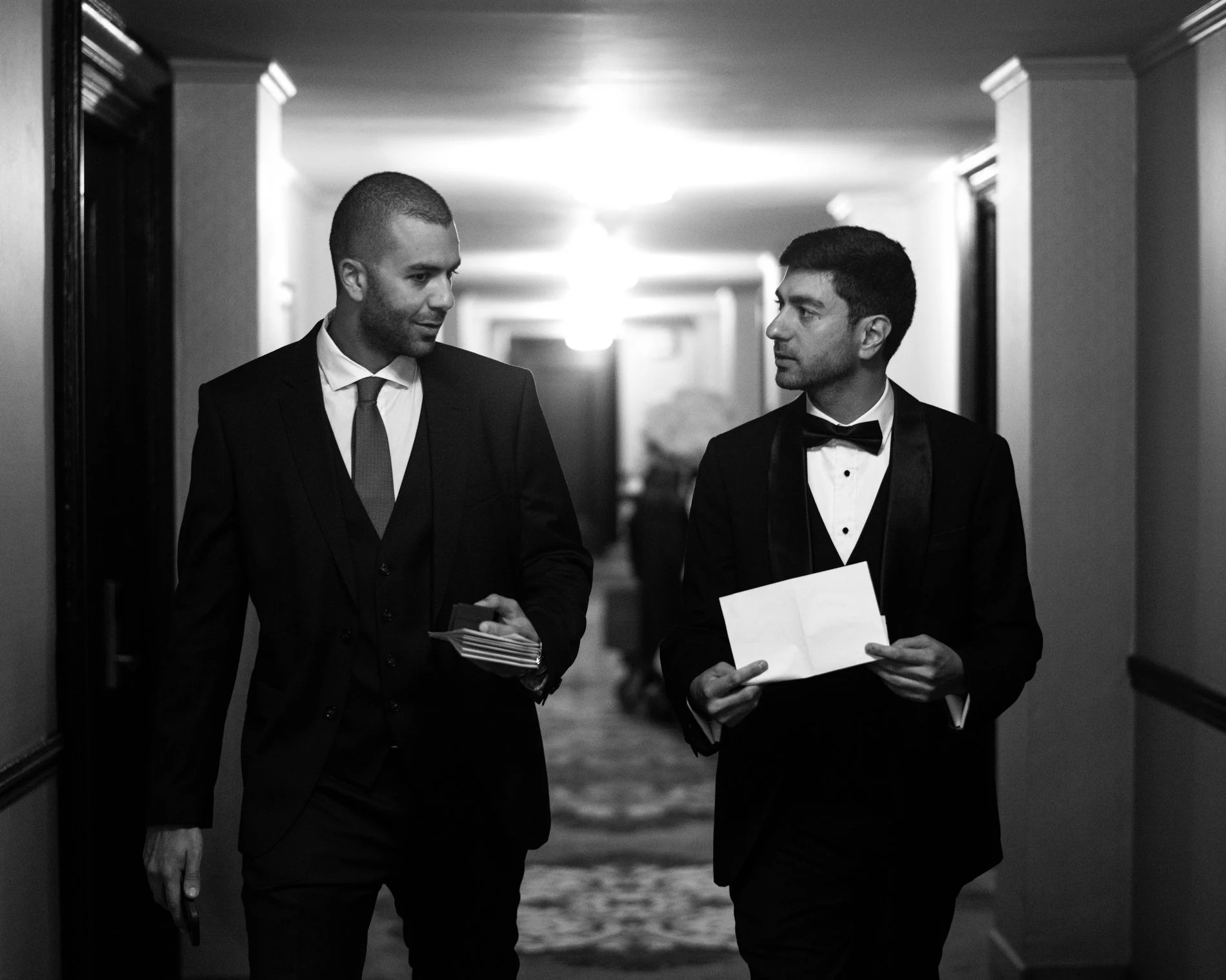 A groom and his friend walk together and discuss speech details during a Boston wedding photojournalism session.