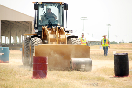  Marlon Cole guides a barrel through part of the obstacle course for the Rubber Tired Loader as Road-E-O judges look on. 