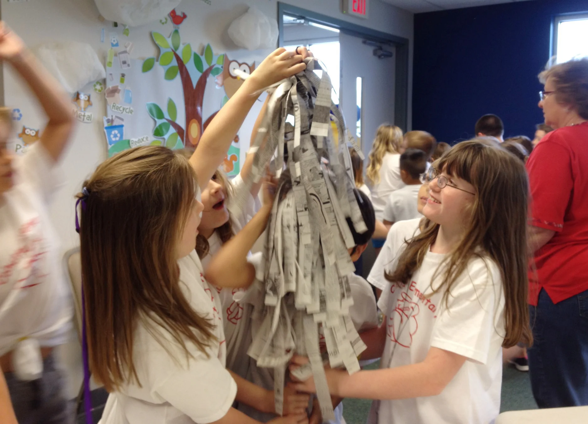 Students on a tour make a tree grow out of newspaper during an activity in the education room.