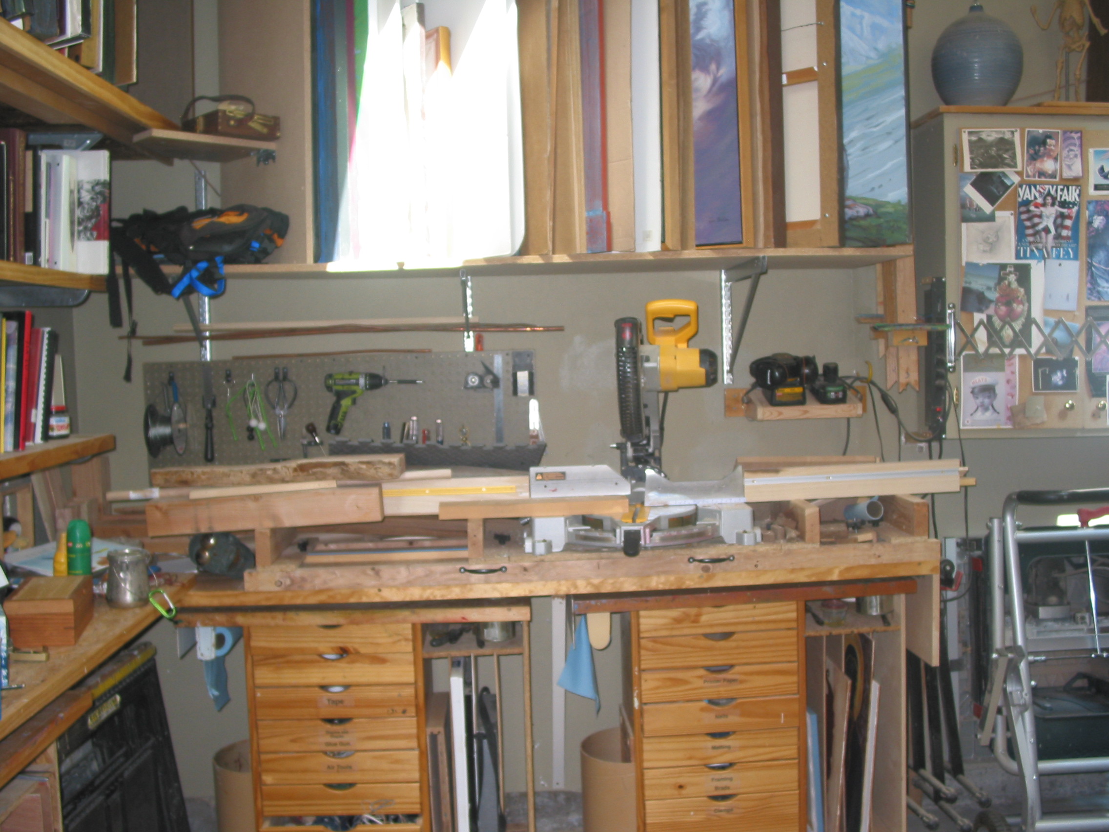 Pictured here is my Chop Saw and table. The drawers you see underneath are rolling easels that my painting students use and the mast are hanging on the wall in the upper right. You can see painting storage above it and my art book collection on the left.