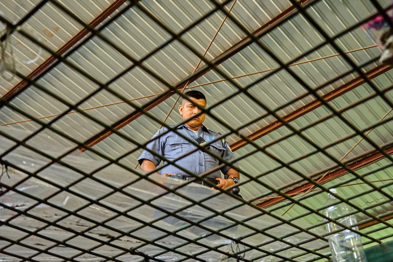  Prison warden looks through the caged roof of a cell in Apanteos prison 