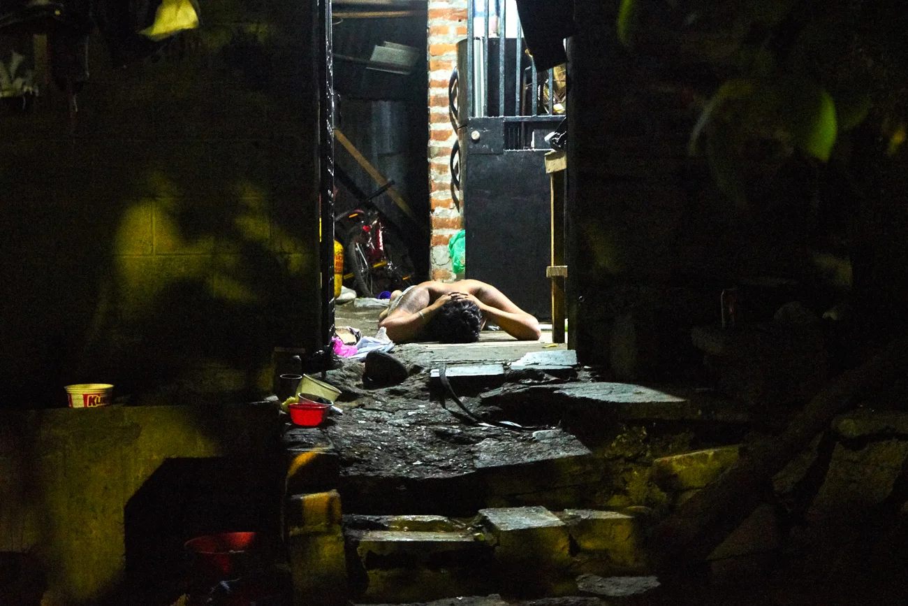  A suspected gang member lays prone on the floor whilst armed police search his home. 