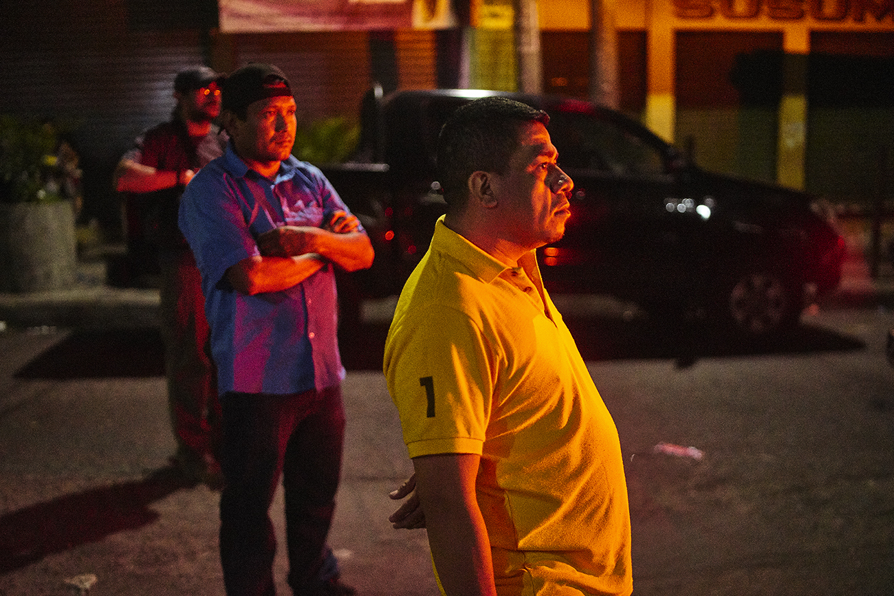 Onlookers at the scene of a shooting homicide in downtown San Salvador. A security guard was shot in a restaurant. His gun was stolen in the incident.