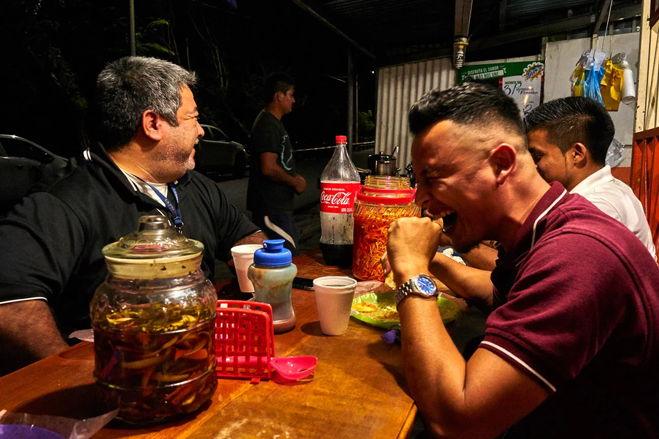  Francisco (left) a night-shift photographer for popular national tabloid newspaper La Prensa Grafica, enjoys pupusas with colleagues during a short break on a busy Saturday night in San Salvador. 