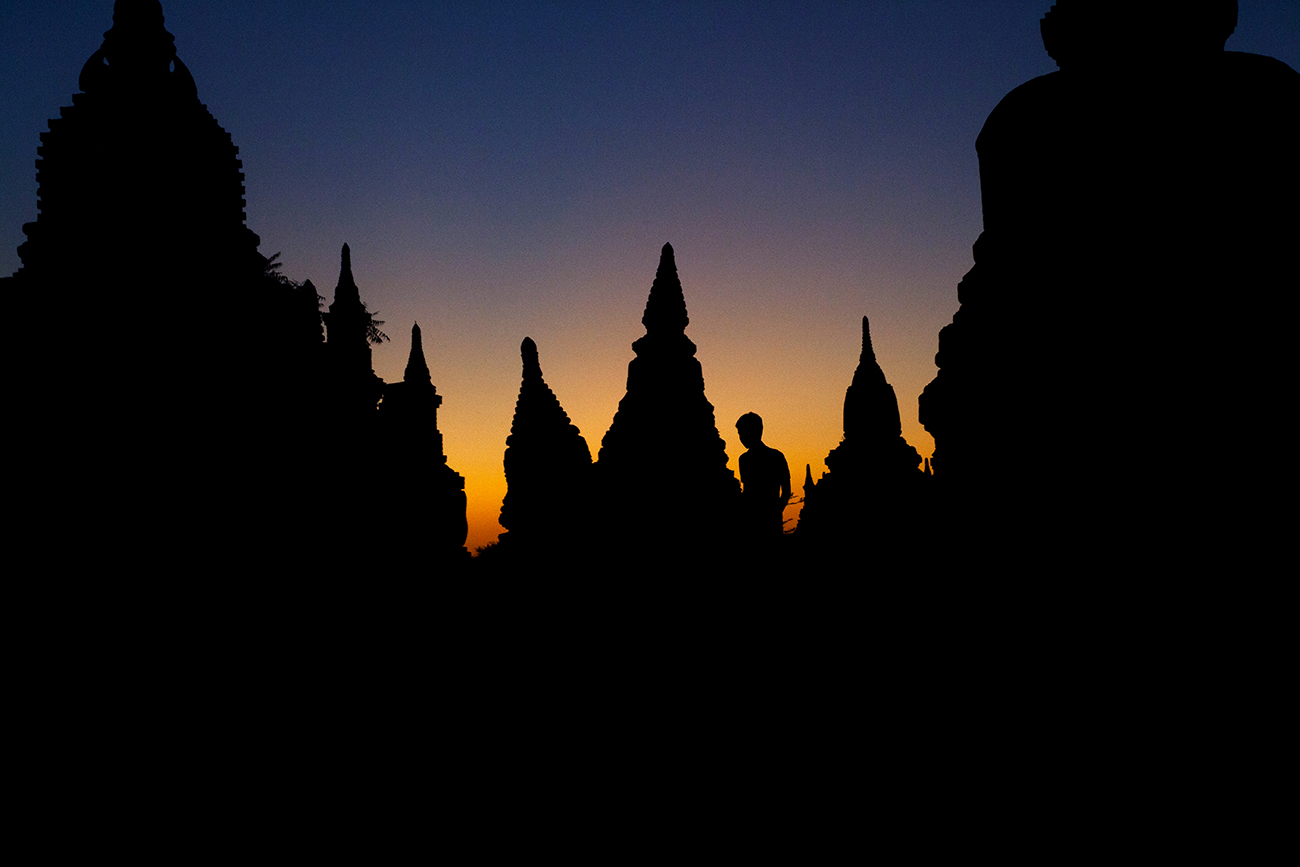 Boy walks among stupas at dusk. Bagan, Myanmar. 2014.
