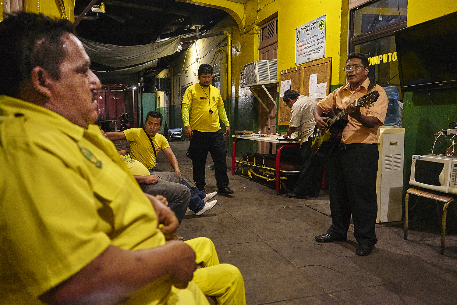 A local musician plays music for volunteers before the evening shift roll call.
