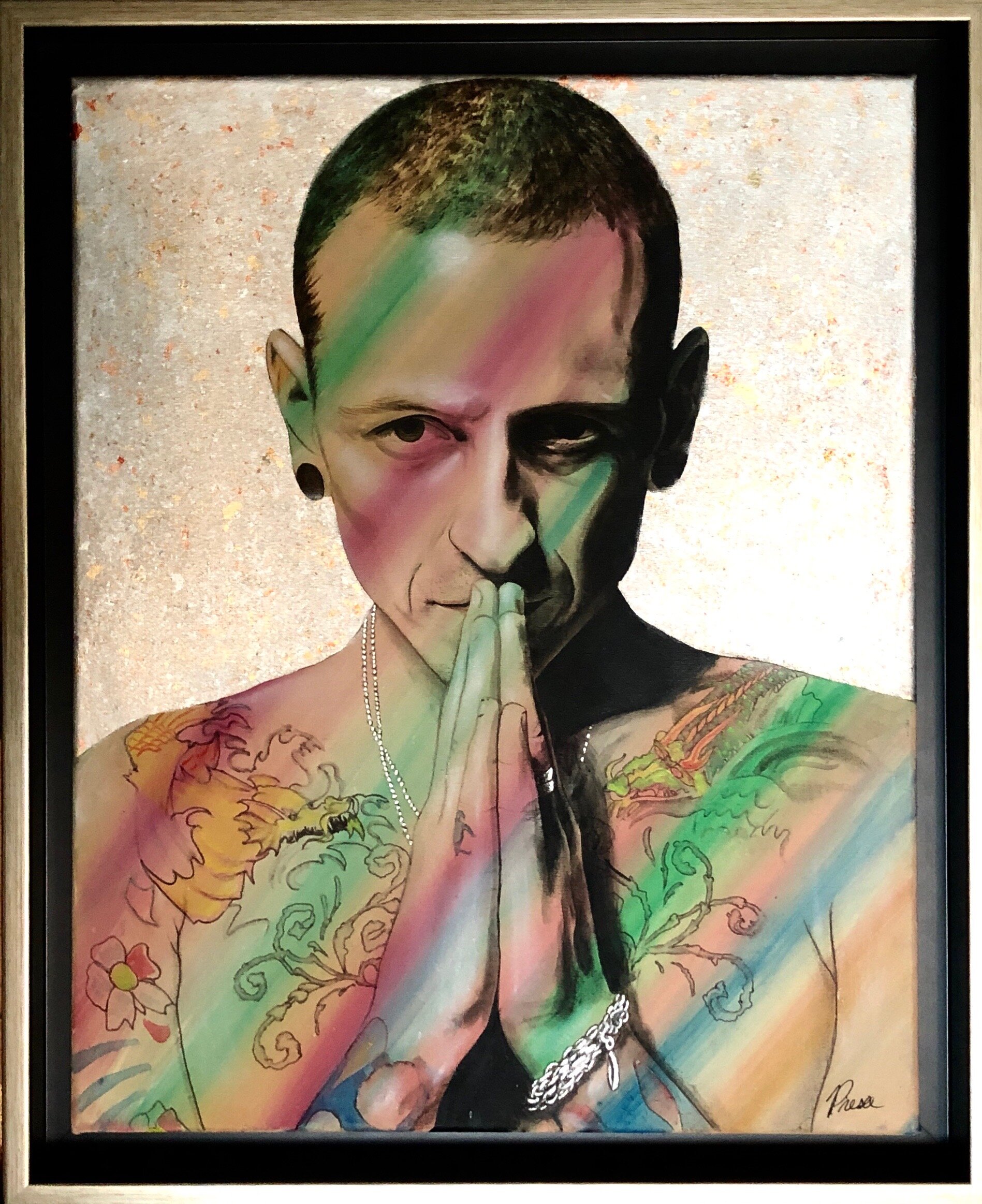 Tattooed man with colorful lighting effect, hands in prayer position.