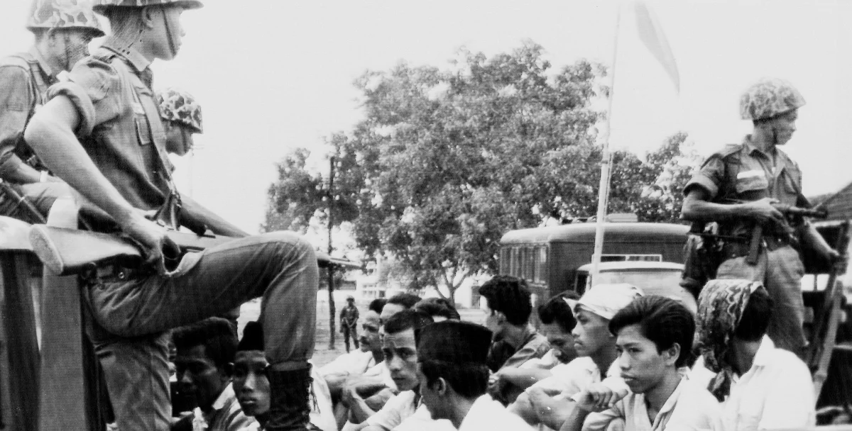 In this Oct. 30, 1965, file photo, members of the Youth Wing of the Indonesian Communist Party (Pemuda Rakjat) are guarded by soldiers as they are taken by open truck to prison in Jakarta. (AP Photo/File)